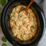 Crock pot Tuscan meatballs with gnocchi and wooden spoon ready to serve.