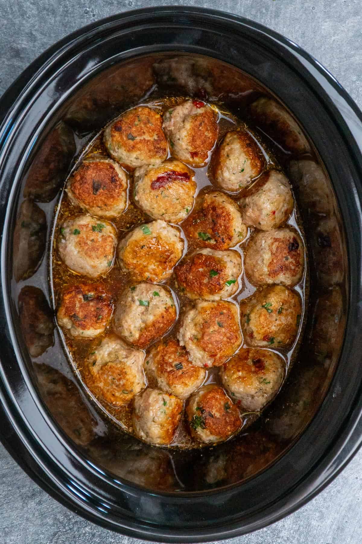 Chicken meatballs, broth, sun dried tomatoes, and seasonings ready to be cooked.