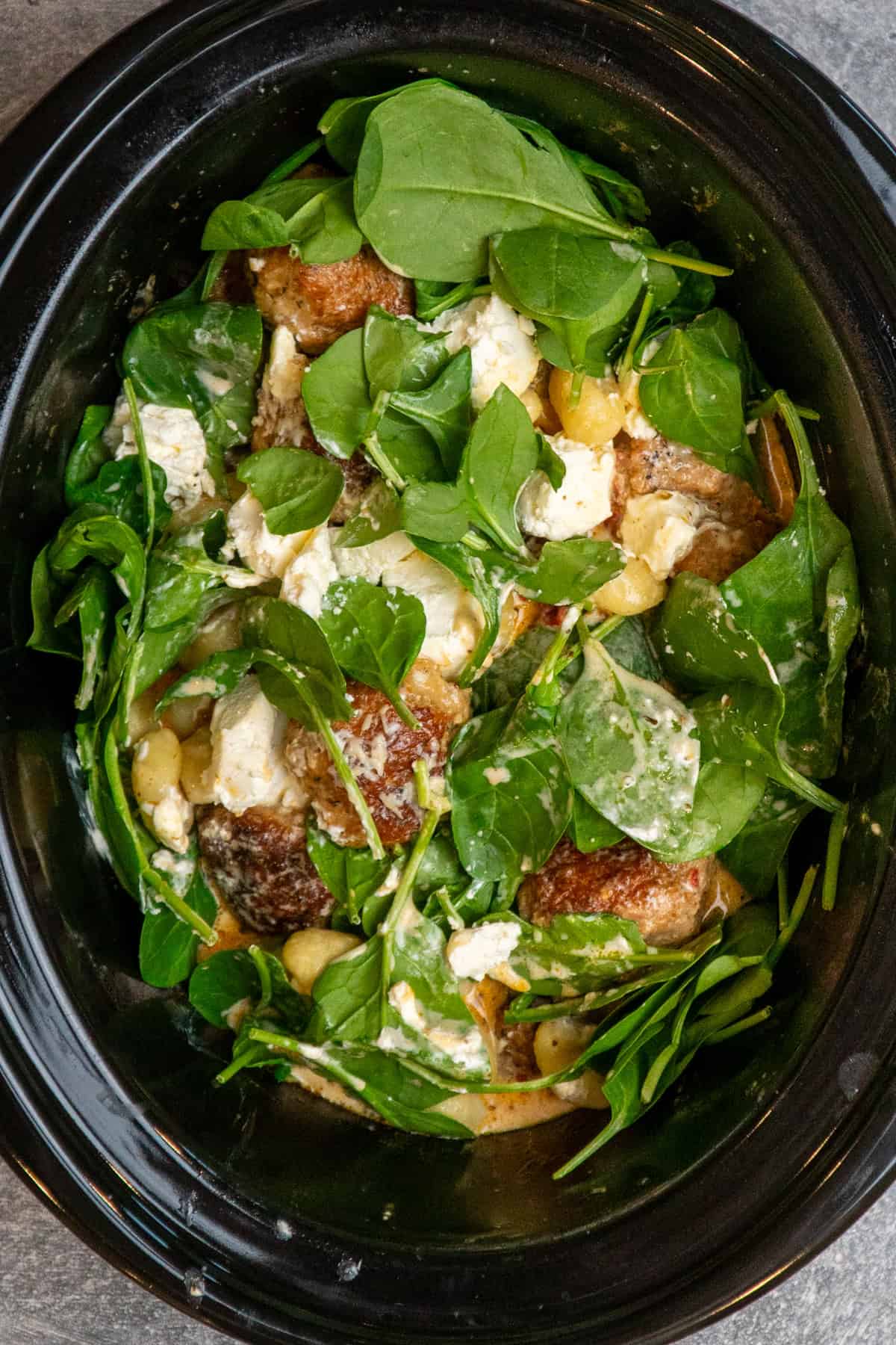 Spinach, cheeses, heavy cream, and gnocchi added to the slow cooker.