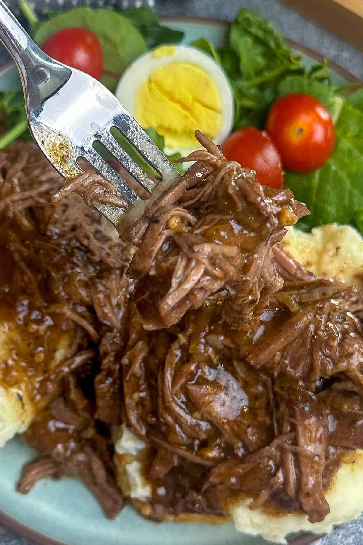 A fork holding a bite of beef Manhattan.