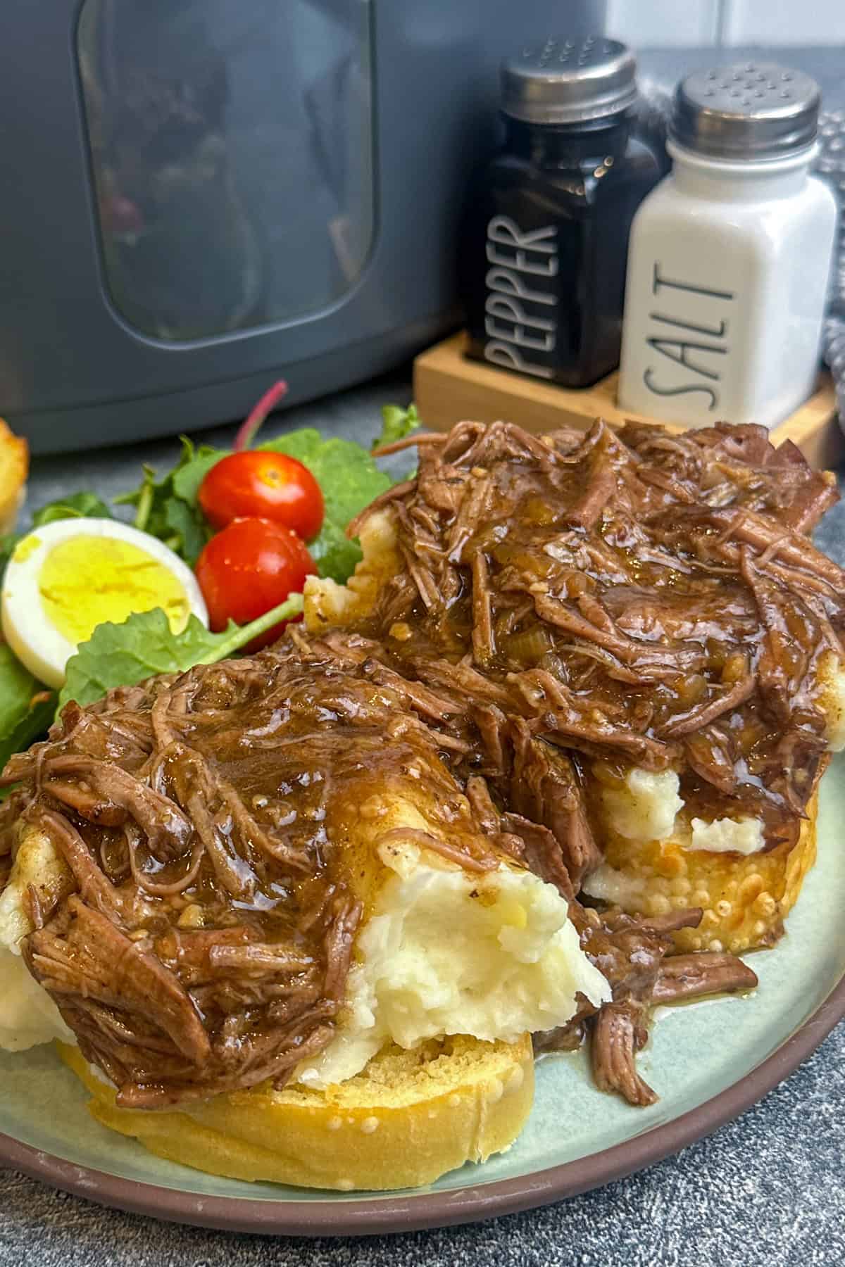 Beef Manhattan over Texas toast and mashed potatoes on a plate.