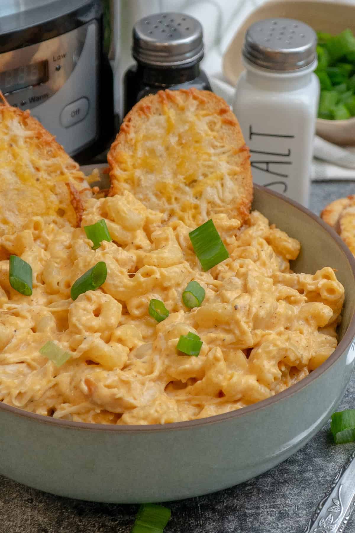 Buffalo chicken mac and cheese in a bow with two pieces of cheese bread.