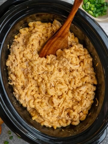 Crock pot buffalo chicken mac and cheese with a wooden spoon in it.