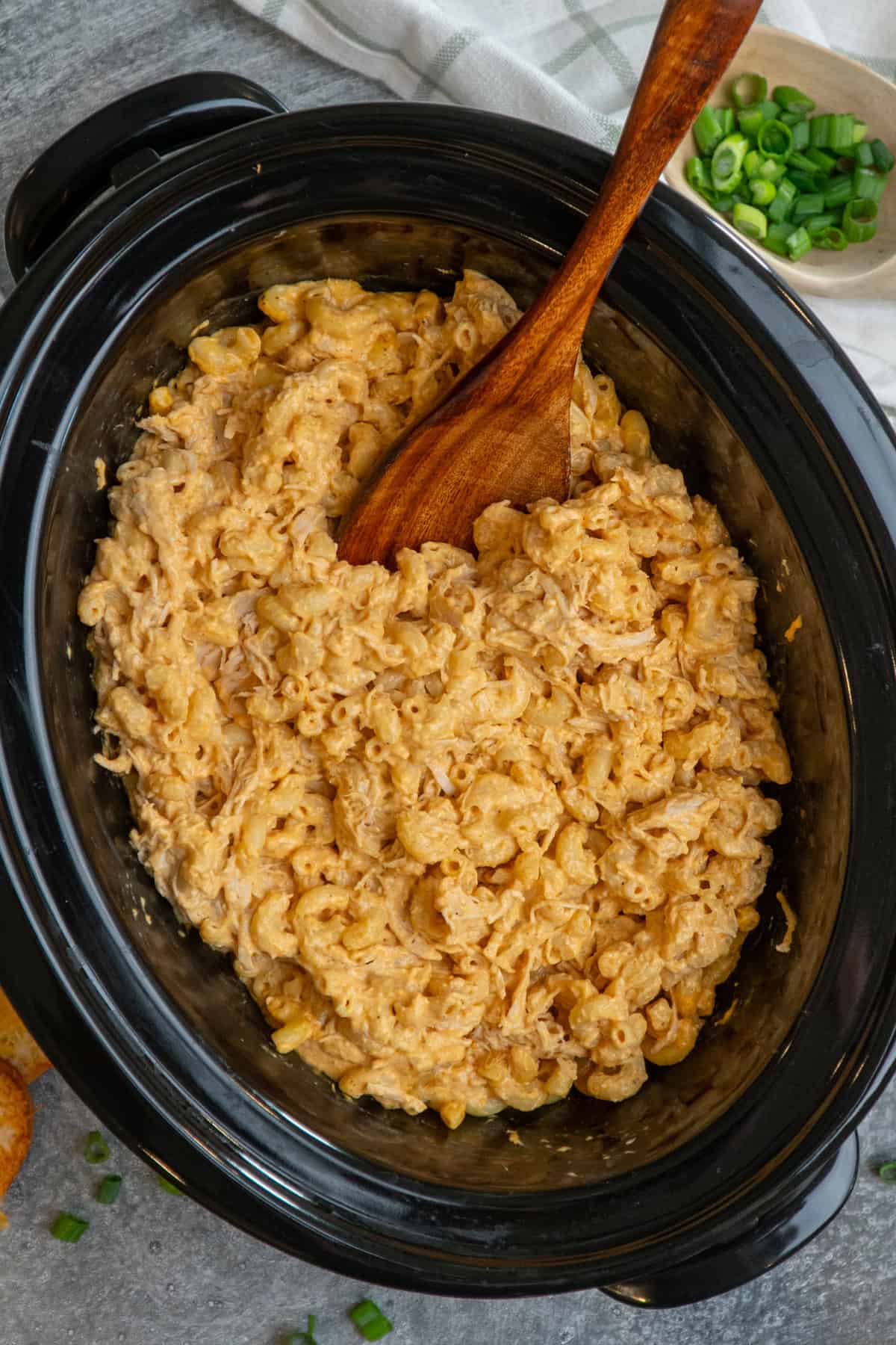 Crock pot buffalo chicken mac and cheese with a wooden spoon in it.