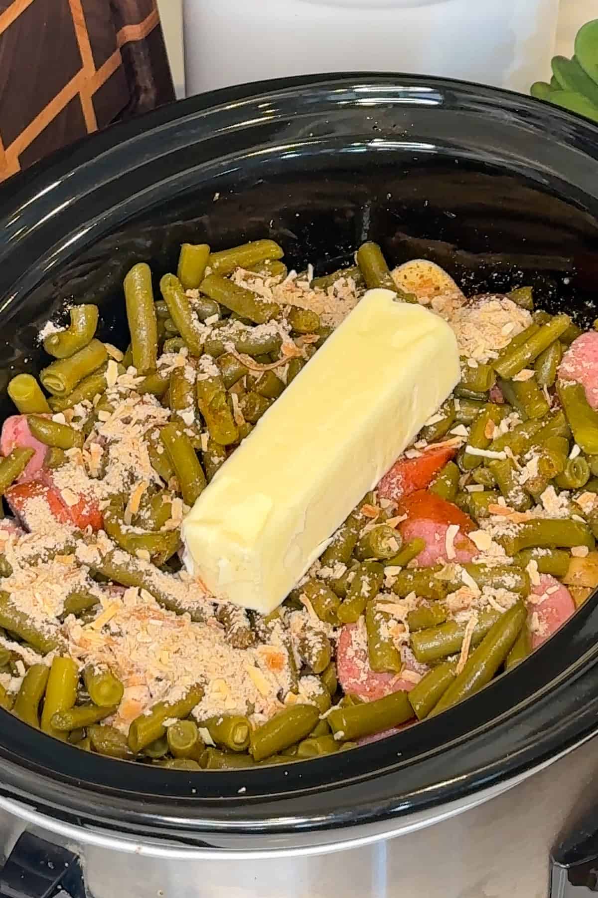 Sausage, green beans, onion soup mix and butter added to the slow cooker.