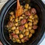 Swamp potatoes in a crock pot with a wooden spoon ready to be served.