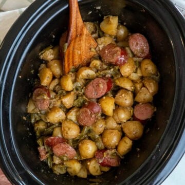 Swamp potatoes in a crock pot with a wooden spoon ready to be served.