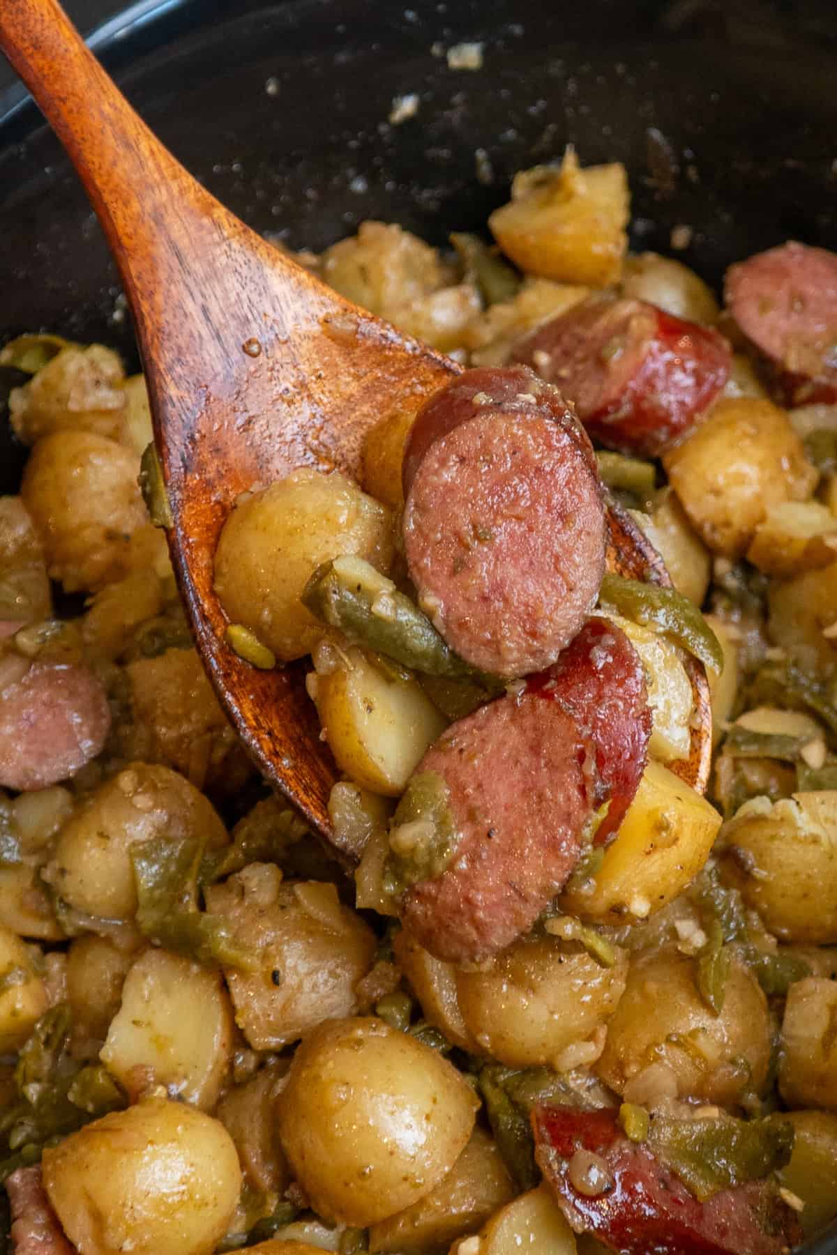 A wooden spoon holding a scoop of swamp potatoes.