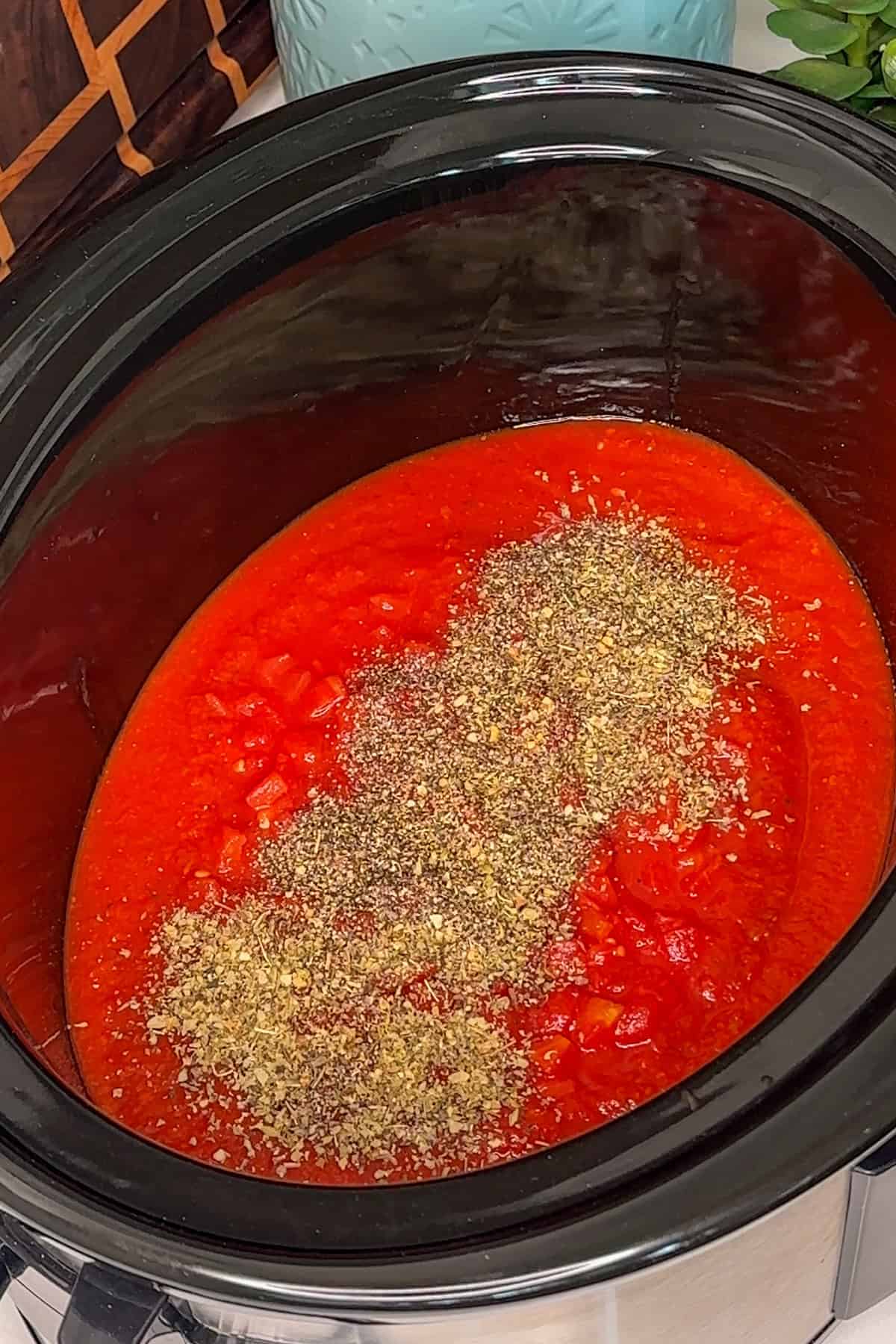 Pasta sauce, diced tomatoes, and seasonings added to a crock pot.