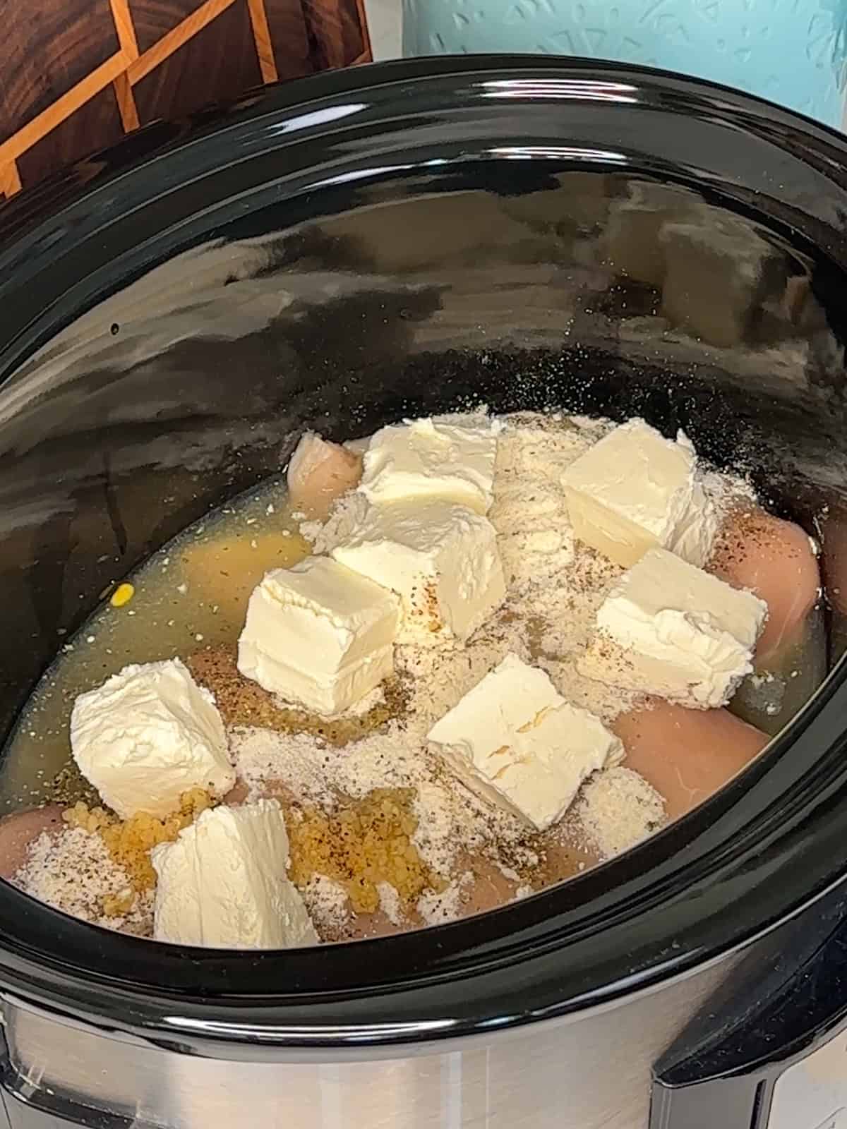 Chicken breast with ranch seasoning, garlic, black pepper, and cream cheese in a slow cooker.